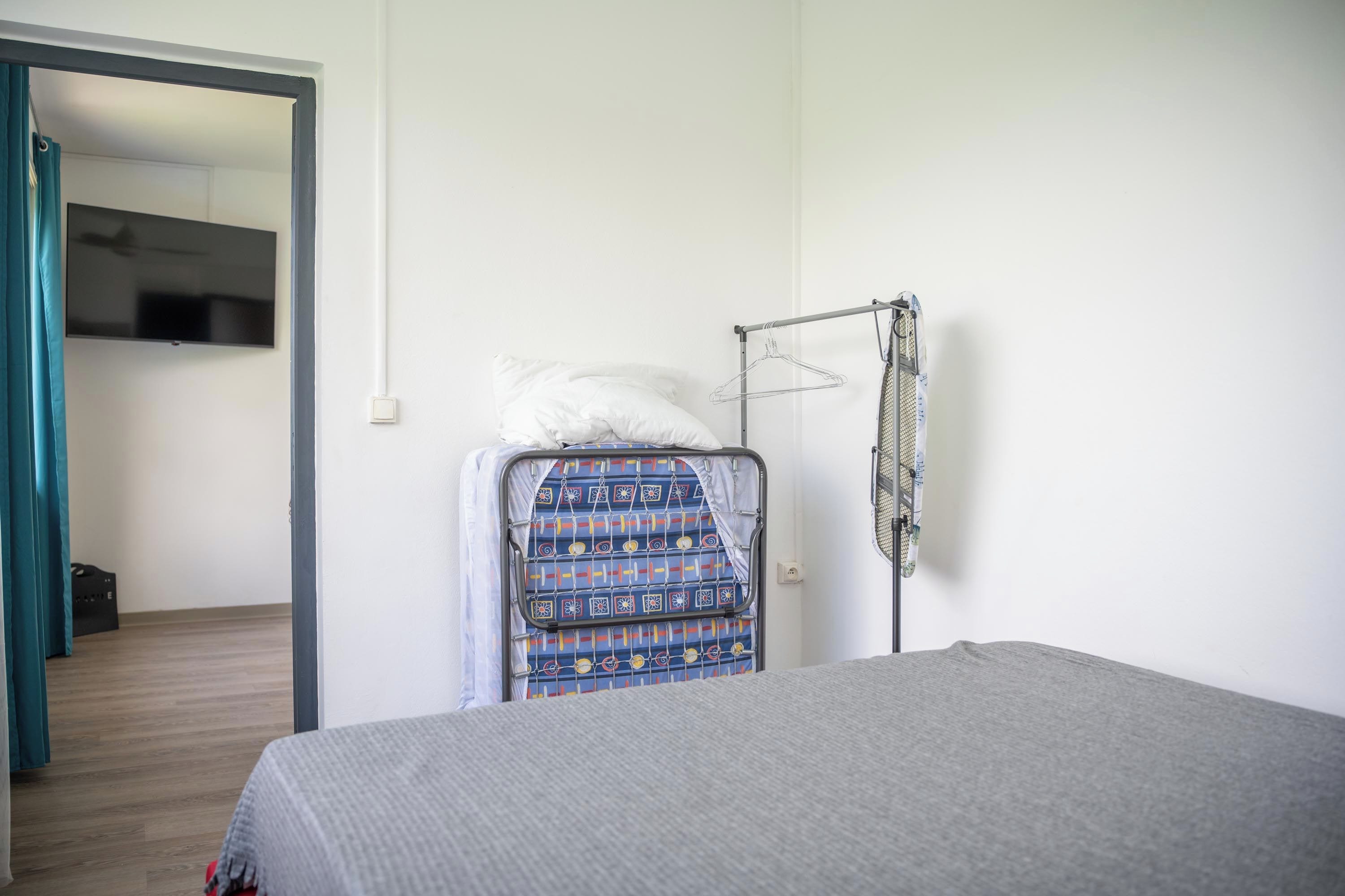 Una camera da letto con un letto, un appendiabiti e un televisore a parete.