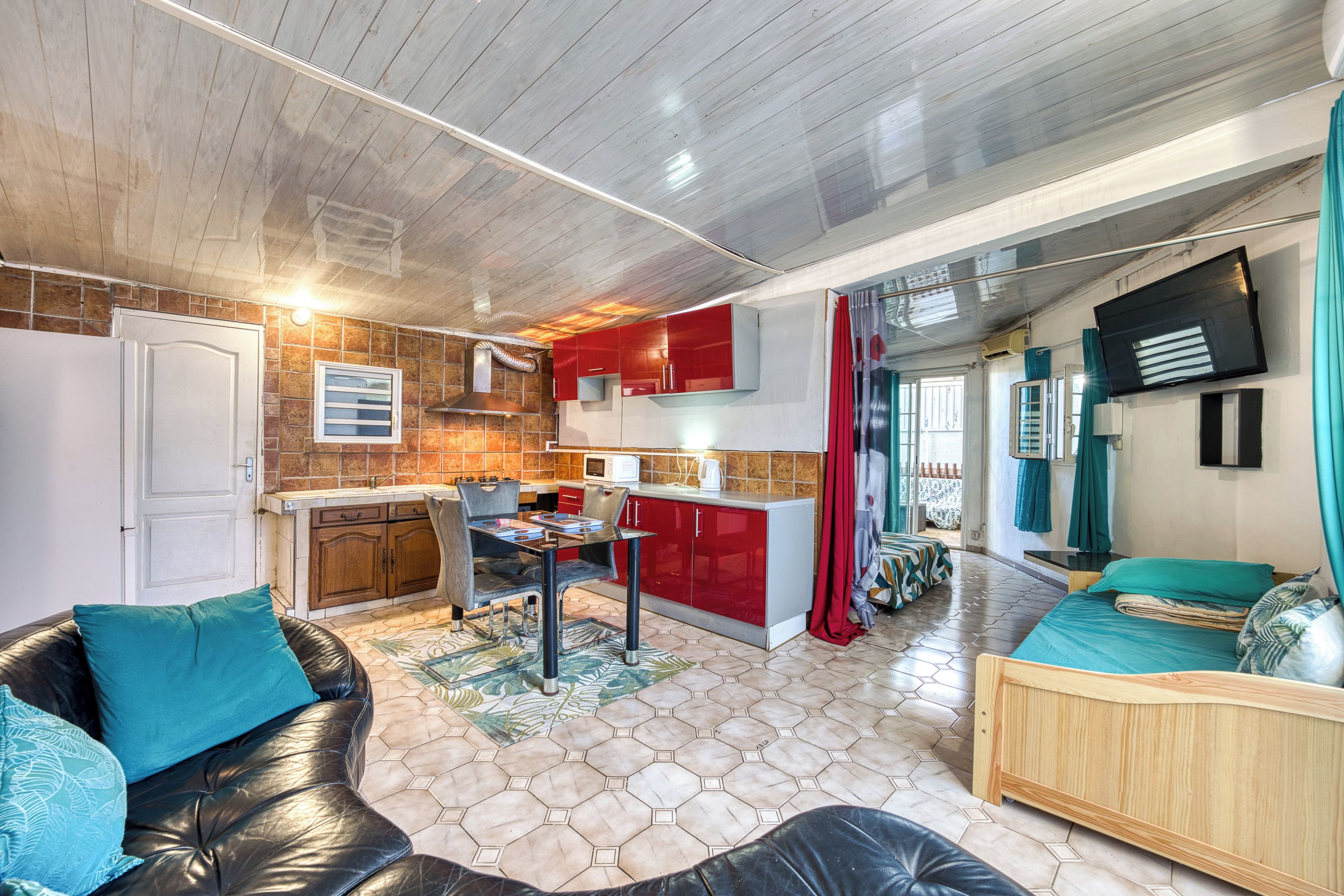 Un espacio habitable compacto con kitchenette, comedor y sala de estar con sofá y cama.