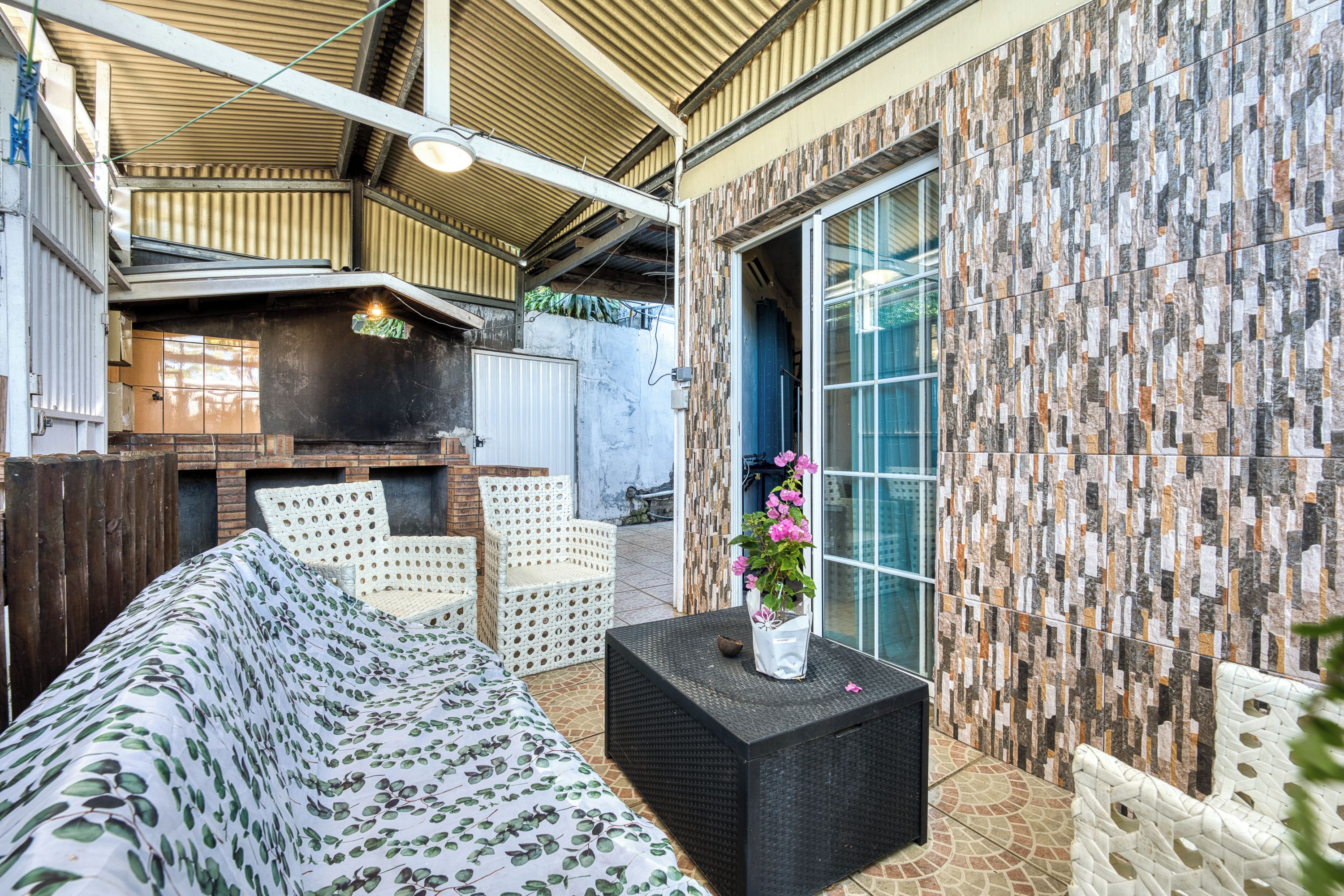An outdoor patio with a sofa, chairs, a table, and a decorative plant.