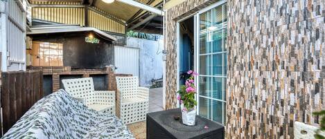 An outdoor patio with a sofa, chairs, a table, and a decorative plant.