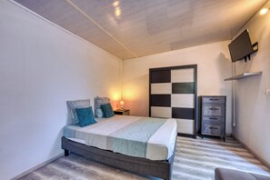 A bedroom with a bed, bedside tables, a TV, and a wardrobe. - Petit Salomon - Jardin - Proche plage (Saint-Pierre)