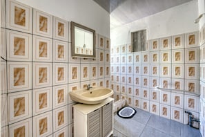 A bathroom with a sink, mirror, and tiled walls. - Petit Salomon - Jardin - Proche plage (Saint-Pierre)