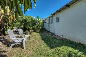 A white building with a small garden area, two white plastic chairs, and a water tank on the side. - Petit Salomon - Jardin - Proche plage (Saint-Pierre)