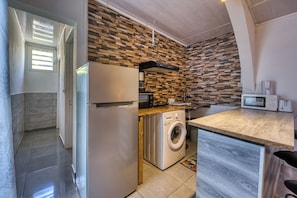 A compact kitchen with a washing machine, a microwave, and a refrigerator. - Petit Salomon - Jardin - Proche plage (Saint-Pierre)
