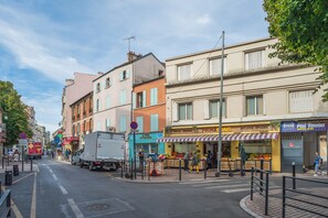 A street view with buildings, a fruit stand, and a truck parked on the side. - La Seinette - Proche gare - Wifi (Argenteuil)