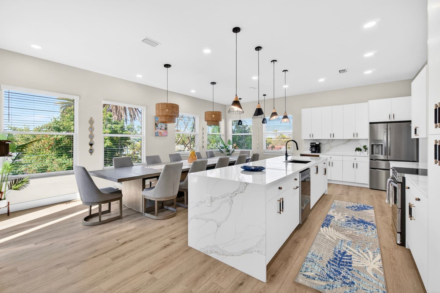 A modern kitchen with white cabinetry, a marble island, and stainless steel appliances.