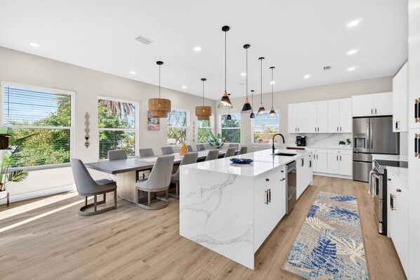 A modern kitchen with white cabinetry, a marble island, and stainless steel appliances.