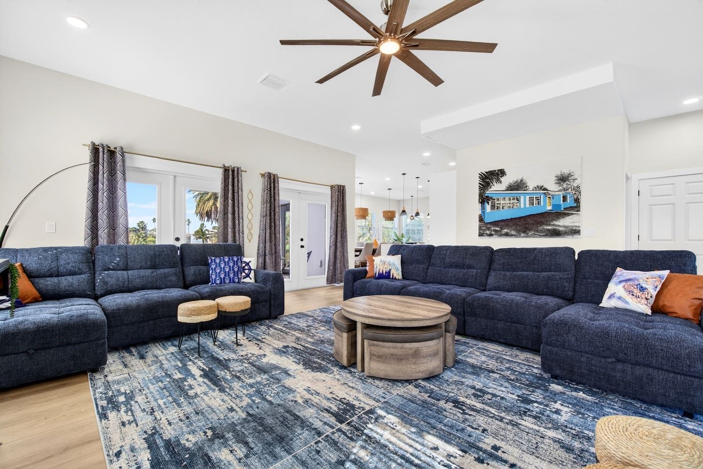A modern living room with two sofas, a coffee table, and a ceiling fan.