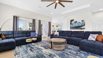 A modern living room with two sofas, a coffee table, and a ceiling fan.