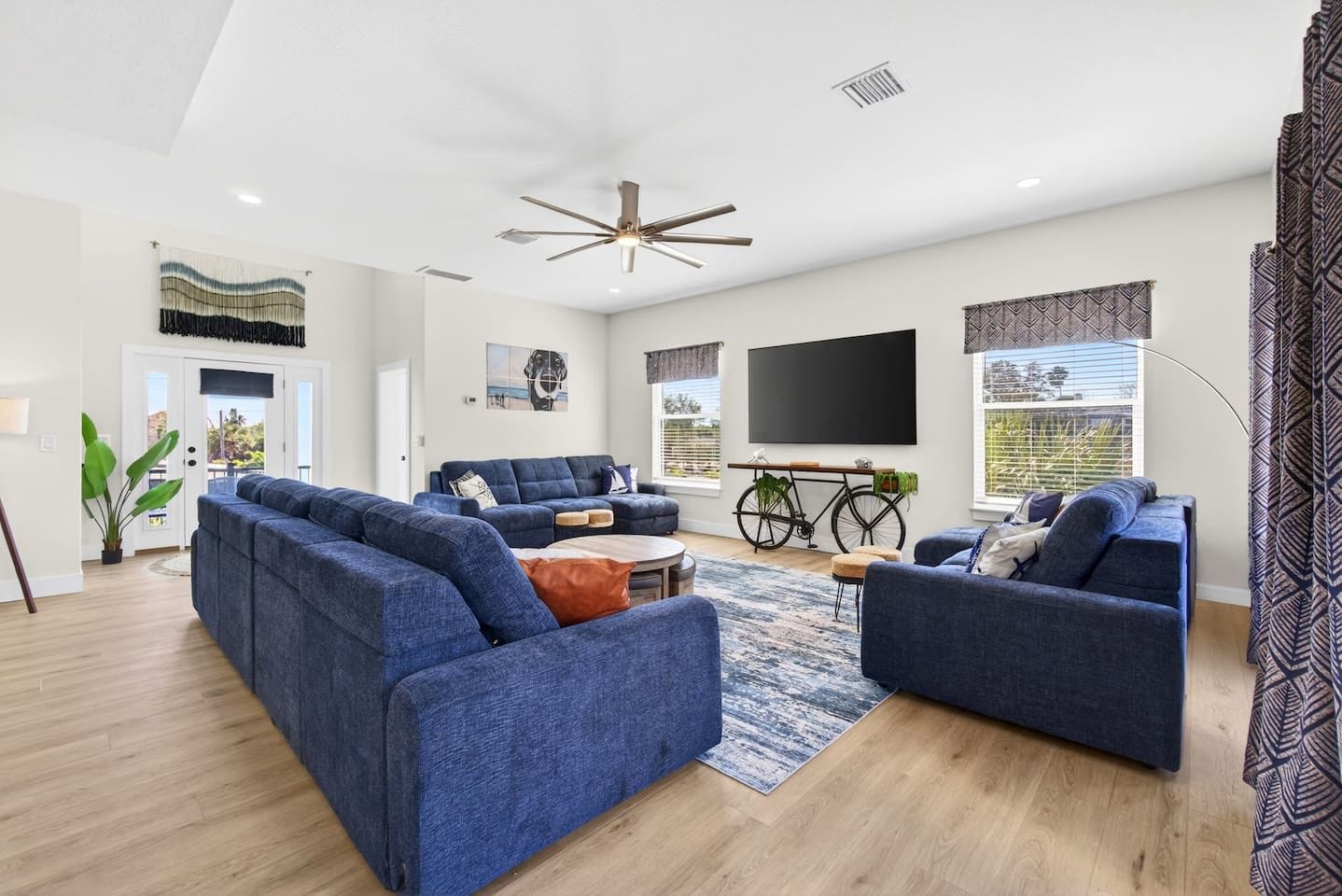 A modern living room with a sectional sofa, a coffee table, a TV, and a bicycle.