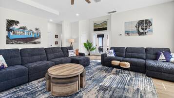 A modern living room with two grey sofas, a round wooden coffee table, and a patterned rug.