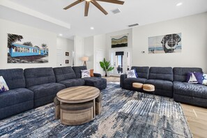 A modern living room with two grey sofas, a round wooden coffee table, and a patterned rug.