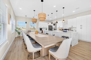 A modern kitchen with white cabinets, a wooden island, and pendant lighting.