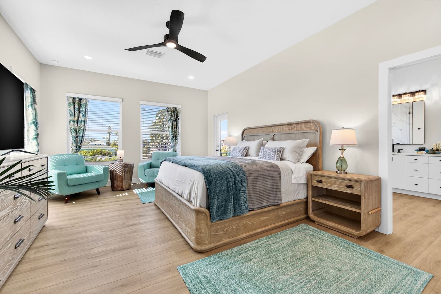 A bedroom with a bed, bedside tables, a chair, a TV, and a ceiling fan.
