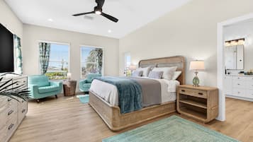 A bedroom with a bed, bedside tables, a chair, a TV, and a ceiling fan.