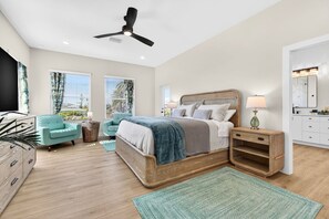 Un dormitorio con cama, mesitas de noche, una silla, televisor y ventilador de techo.