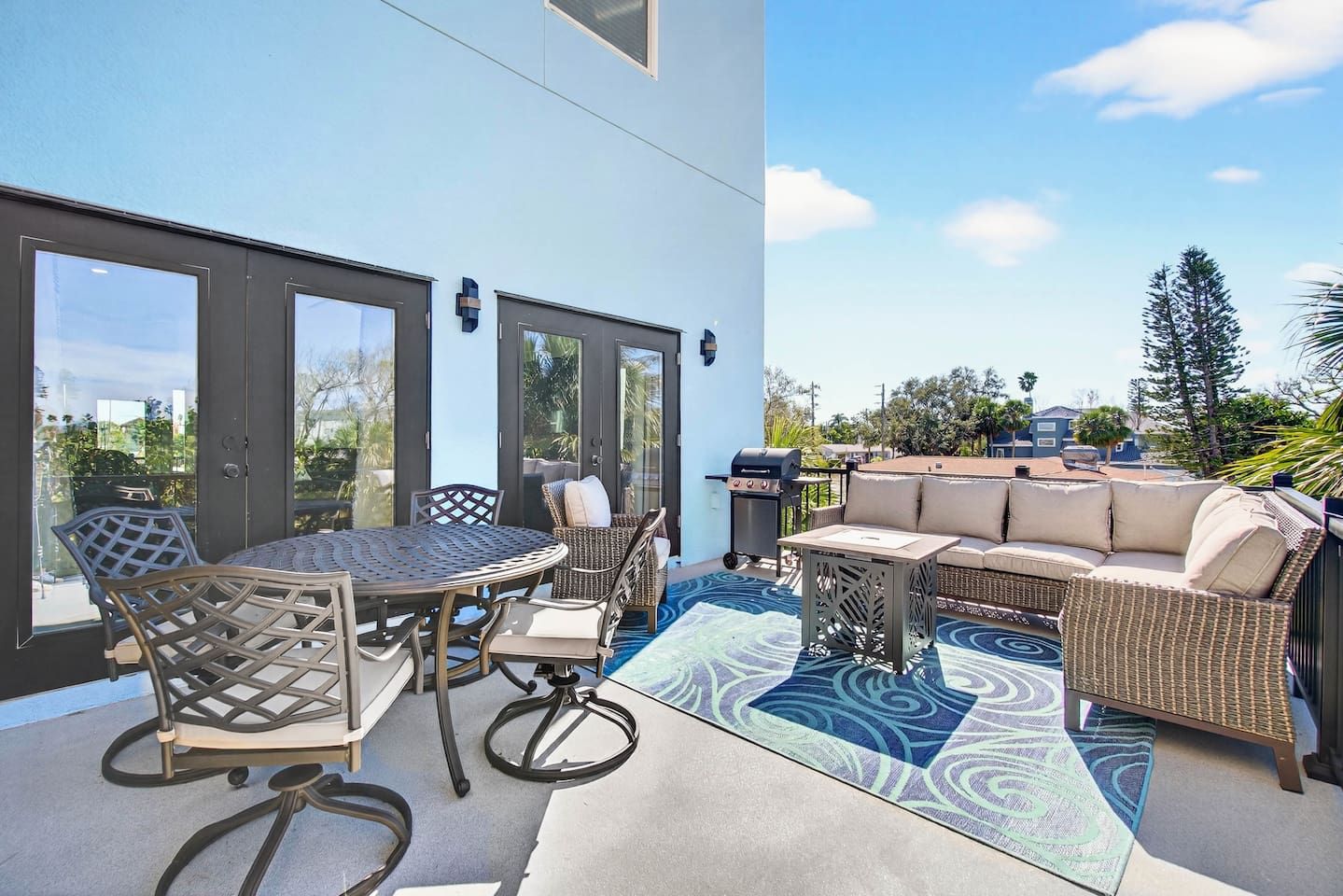 An outdoor patio with a round table and chairs, a sofa, and a grill.