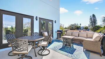 An outdoor patio with a round table and chairs, a sofa, and a grill.