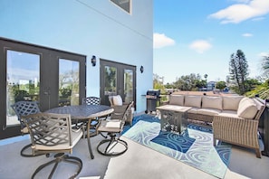 An outdoor patio with a round table and chairs, a sofa, and a grill.