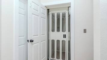 A white door with a glass panel, a white wall, and a wooden floor.