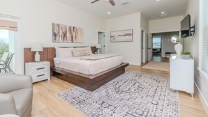 A bedroom with a bed, bedside tables, a ceiling fan, and a view to a balcony. - Spacious Beach Retreat, Sleeps 10 | Walk to Gulf (Redington Beach)