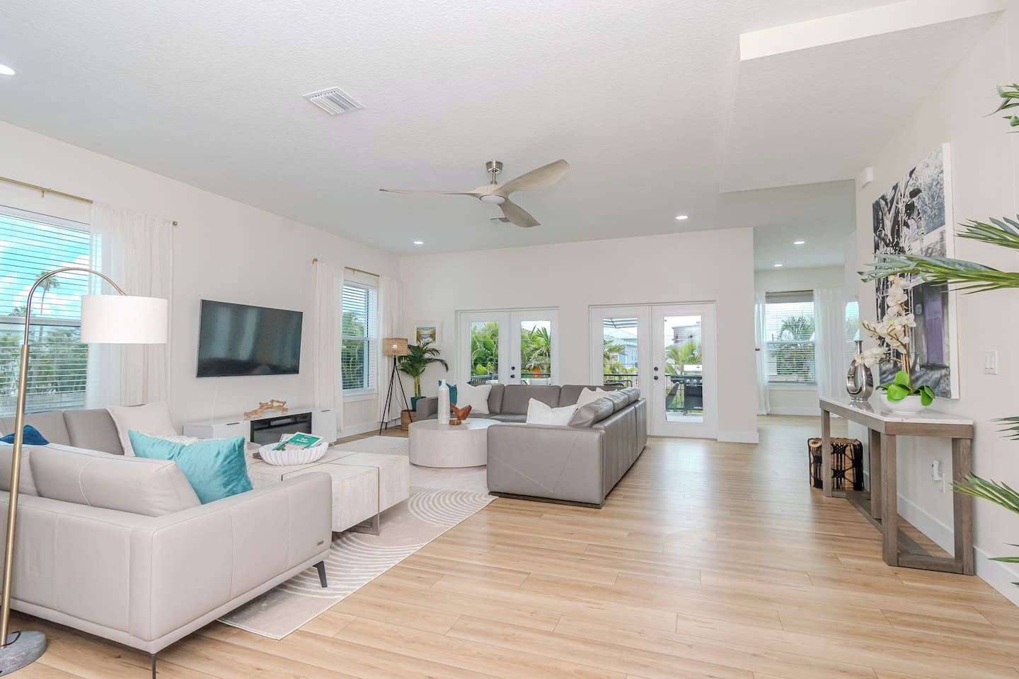 A spacious living area with a flat-screen TV, two sofas, a coffee table, and a ceiling fan.