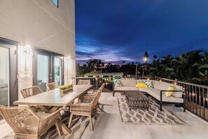 An outdoor patio with a dining table, chairs, and a sofa with cushions.