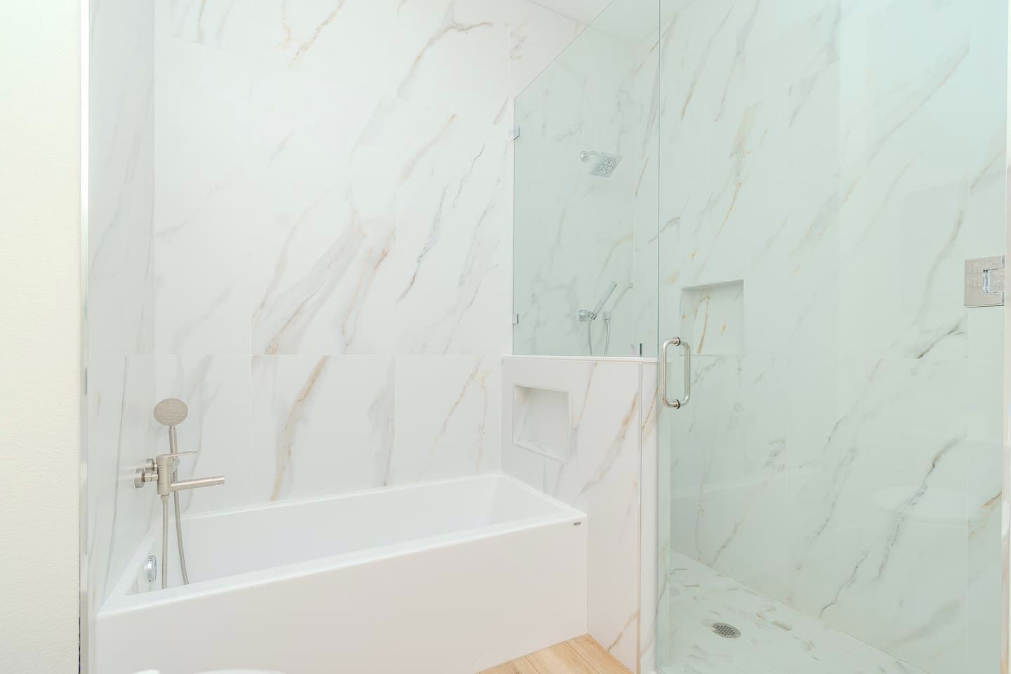 A bathroom with a white bathtub and a glass-enclosed shower area.