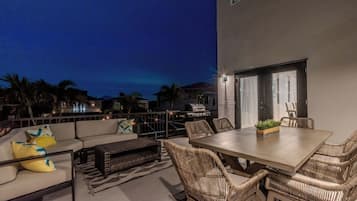 A rooftop patio with a dining table, chairs, and a sofa.