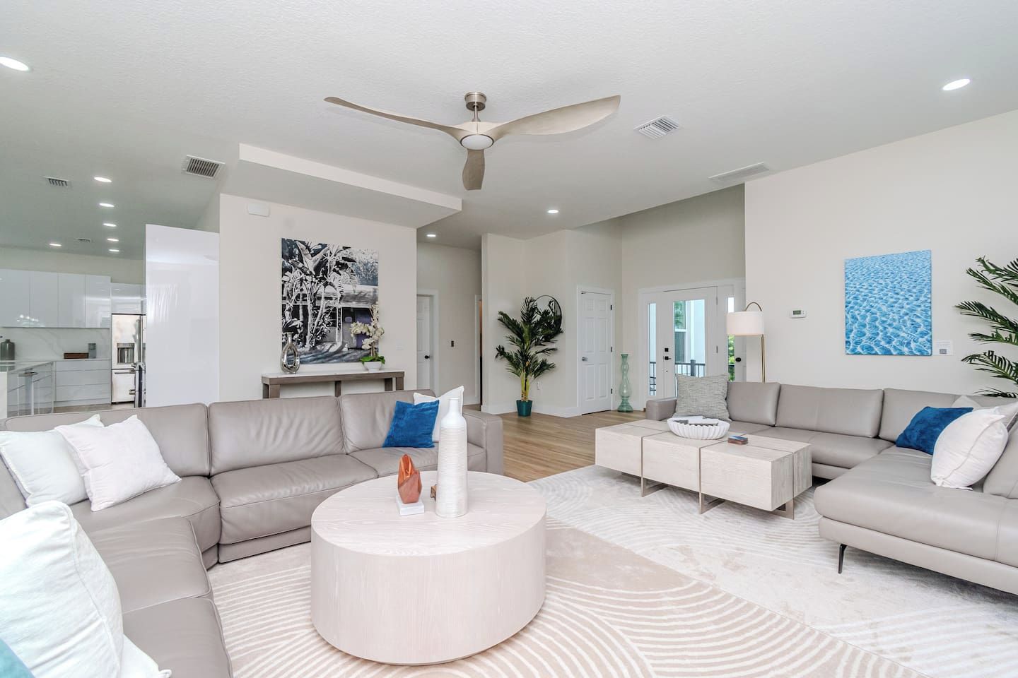A spacious living room with a large sectional sofa, a round coffee table, and a ceiling fan.
