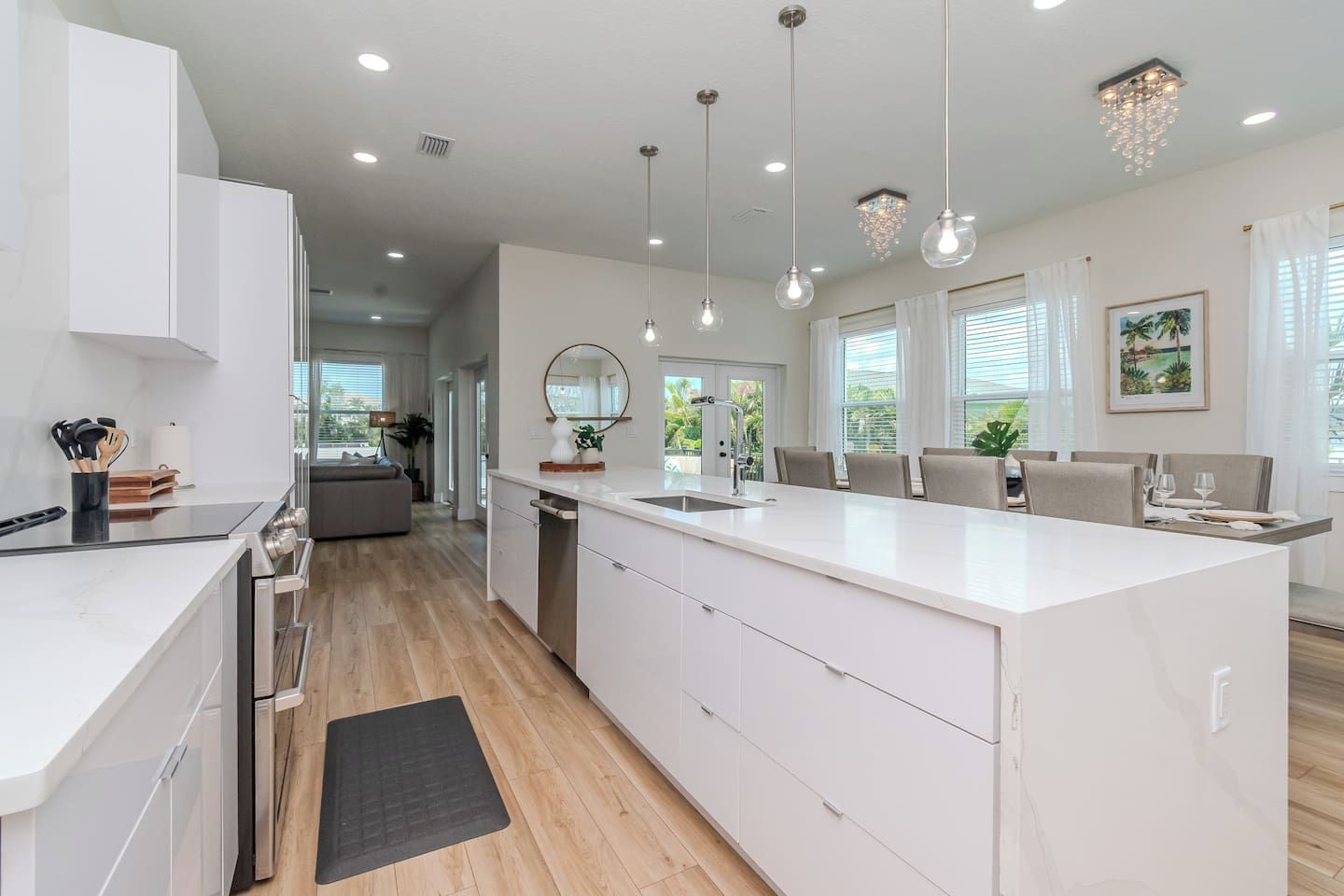 A modern kitchen with a central island, pendant lighting, and a view to the living area.