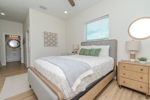 A bedroom with a bed, bedside tables, a mirror, and a window.