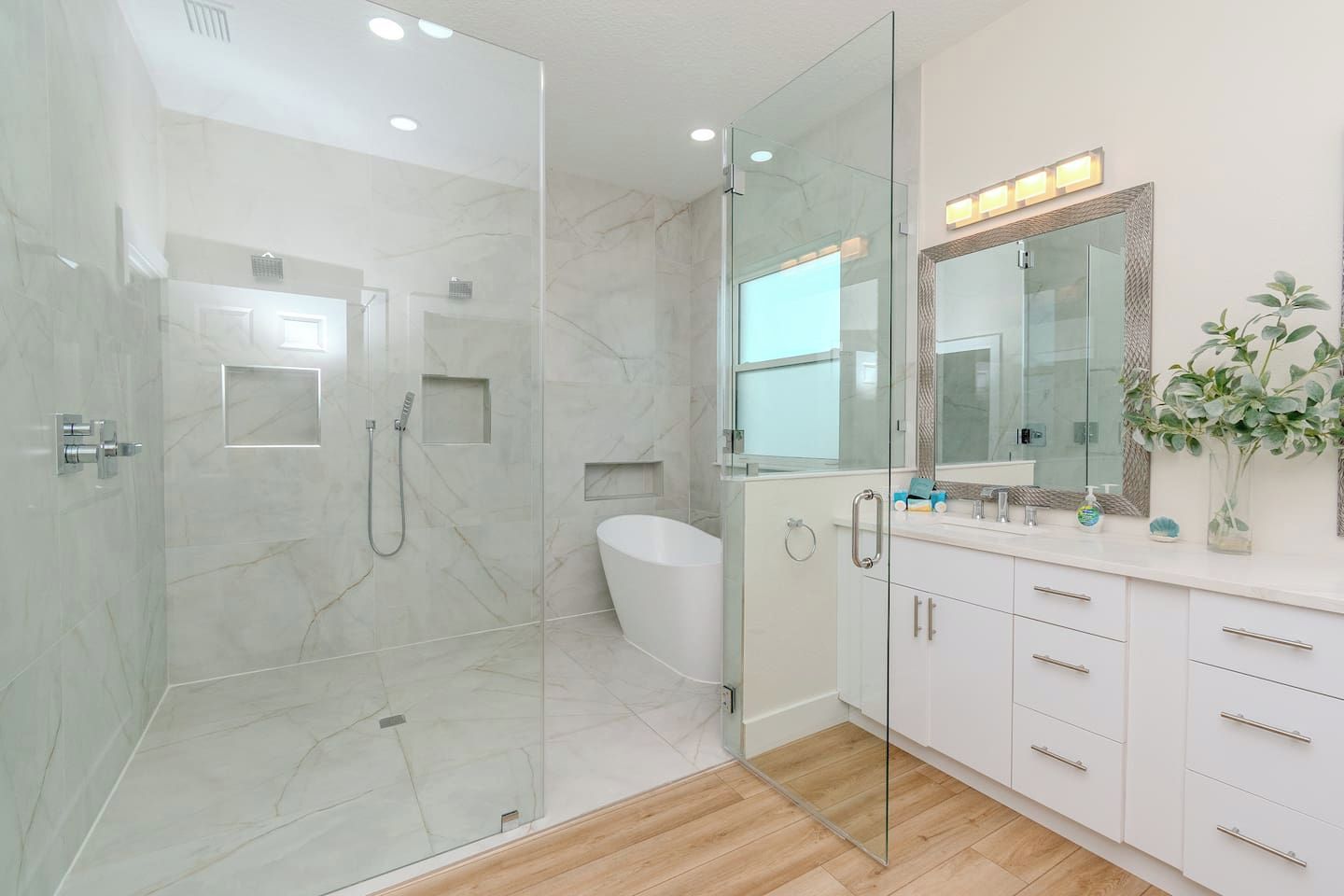 Une salle de bain moderne dotée d’une douche à parois de verre, d’une baignoire sur pieds et d’un meuble-lavabo avec un miroir.