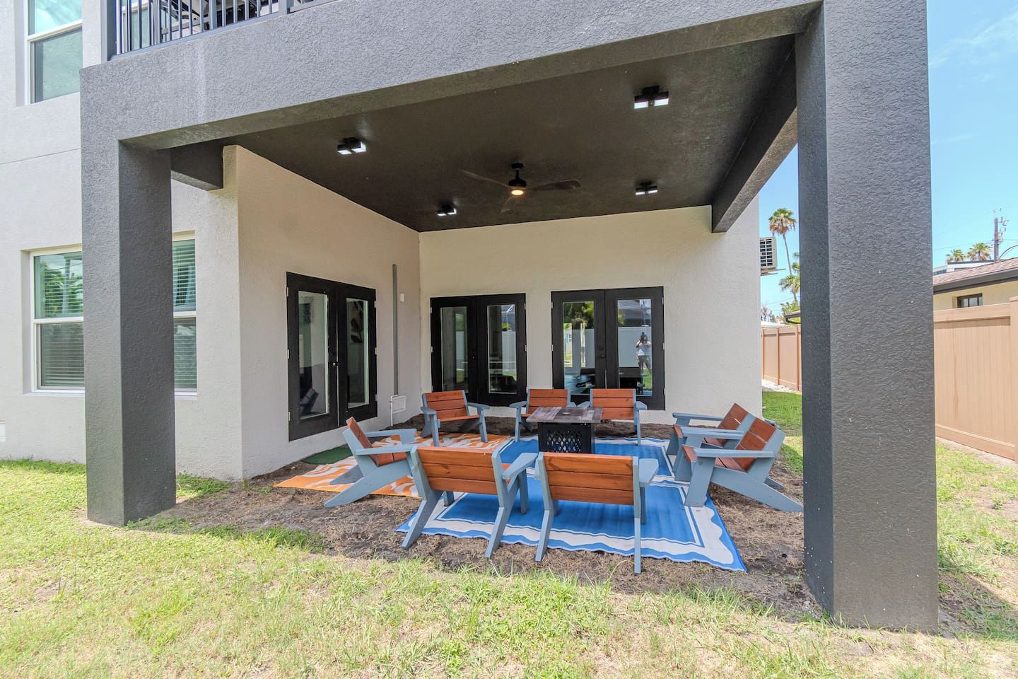 An outdoor patio with a table and chairs, a covered seating area, and a view of the backyard.