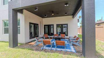 An outdoor patio with a table and chairs, a covered seating area, and a view of the backyard.