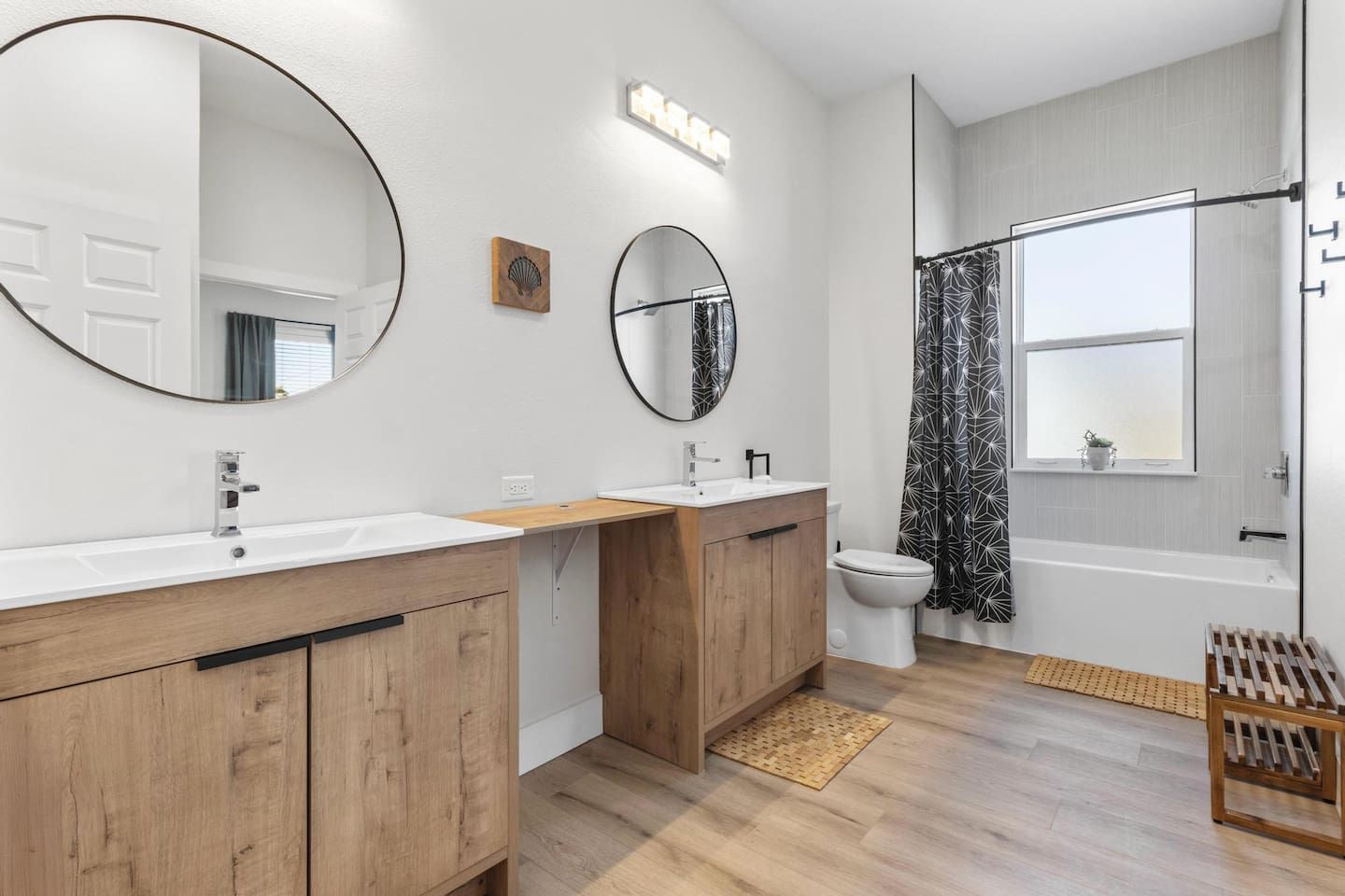 A modern bathroom with two sinks, a toilet, and a bathtub.
