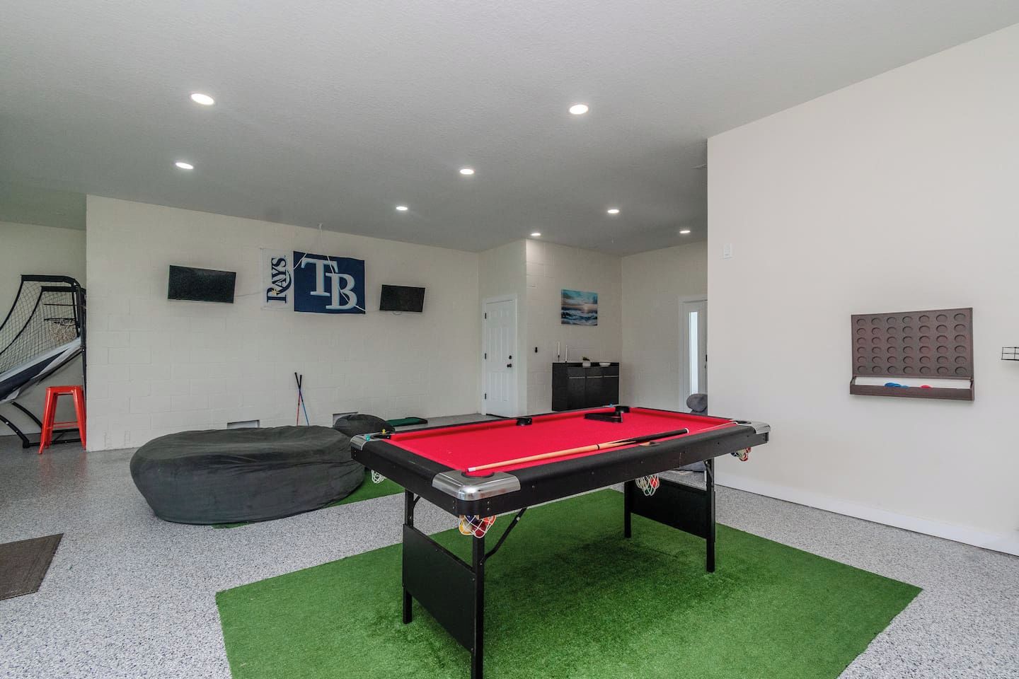 A pool table with a red felt surface, a black bean bag chair, and a small staircase to the left.