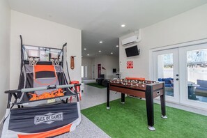 Una habitación con mesa de futbolín, aro de baloncesto y mesa de billar.