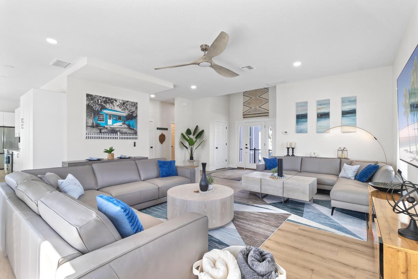 A spacious living room with a large L-shaped sectional sofa, a round coffee table, and a ceiling fan.