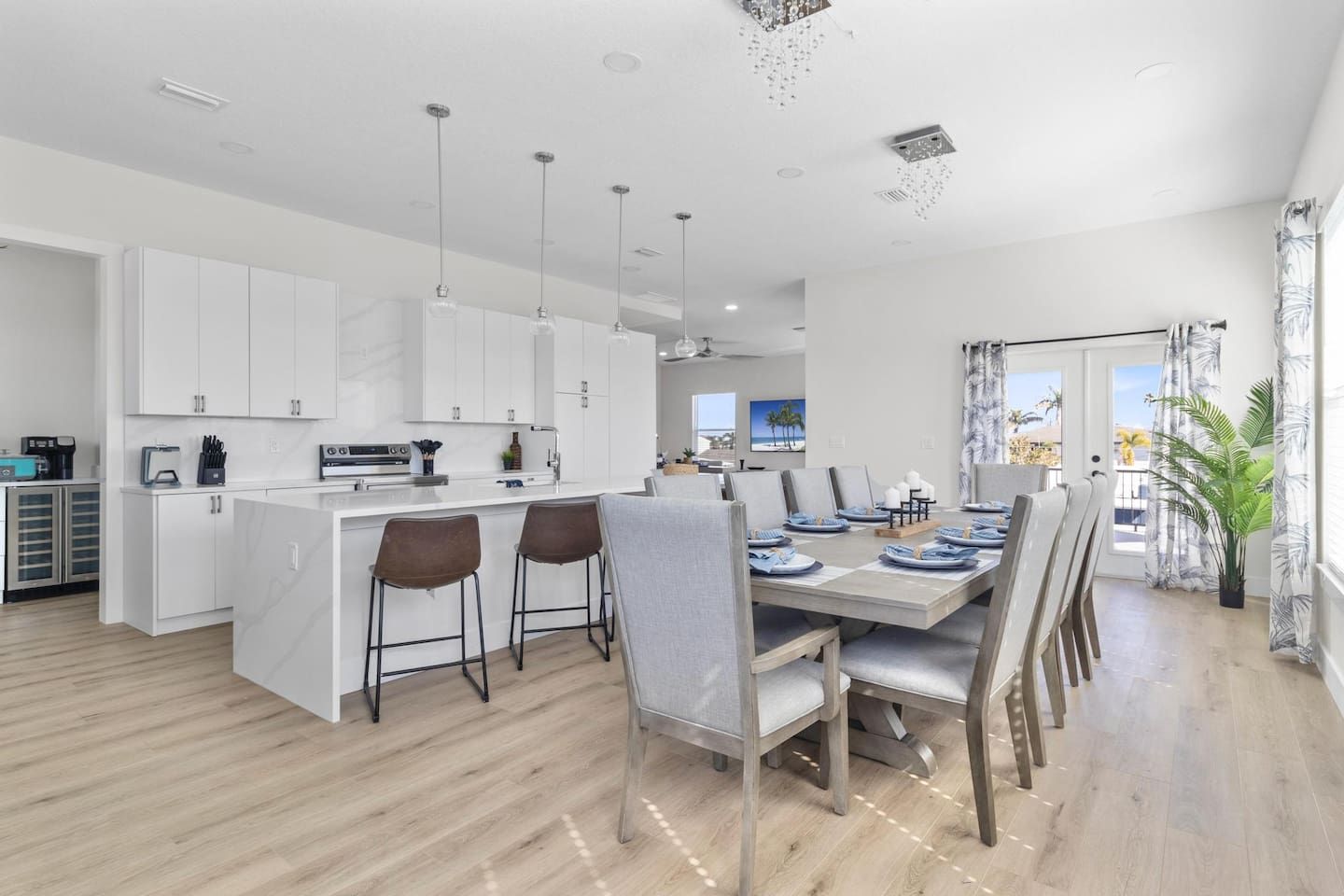 A modern kitchen with white cabinets, a central island, and bar stools.