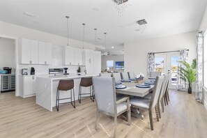 A modern kitchen with white cabinets, a central island, and bar stools.
