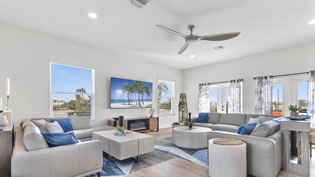 A modern living room with a sofa, coffee table, and a ceiling fan. - 3 Blocks to Redington Beach | Sleeps 10, 6BR (Redington Beach)