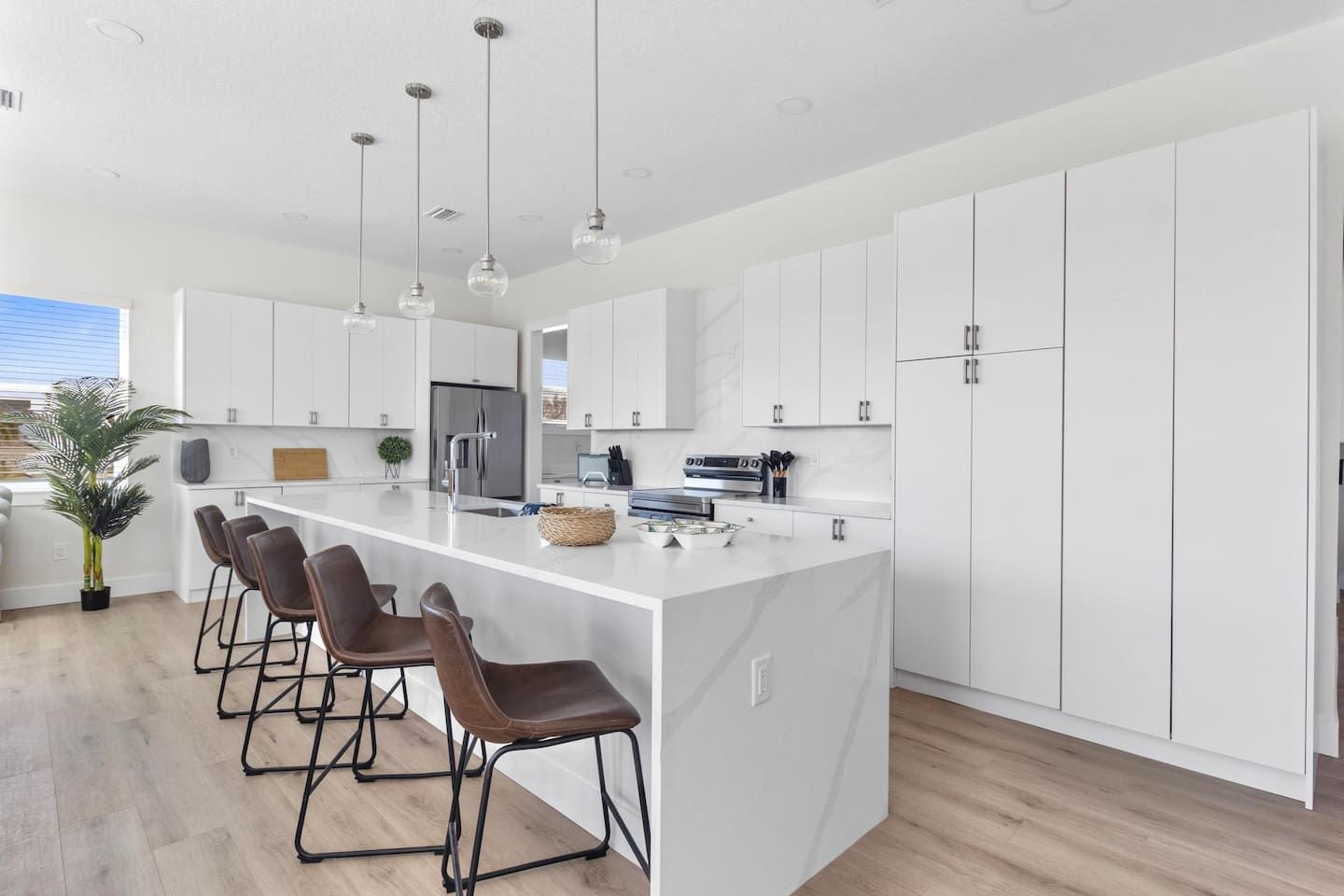 A modern kitchen with a central island, bar stools, and pendant lighting.