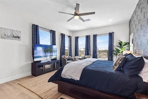 A bedroom with a bed, a TV, and a ceiling fan.