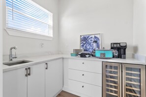 Una cocina moderna con un lavamanos, armarios, una ventana con persianas, una cafetera y una licuadora sobre la encimera.