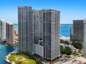A high-rise residential building with a modern glass facade, situated near a waterfront. - ICON BRICKELL IMPRESSIVE 5★ OCEAN/POOL VIEWS @45th (Miami)