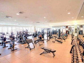 Ein Fitnessstudio mit verschiedenen Trainingsgeräten, darunter Laufbändern, Kraftmaschinen und Kurzhanteln.