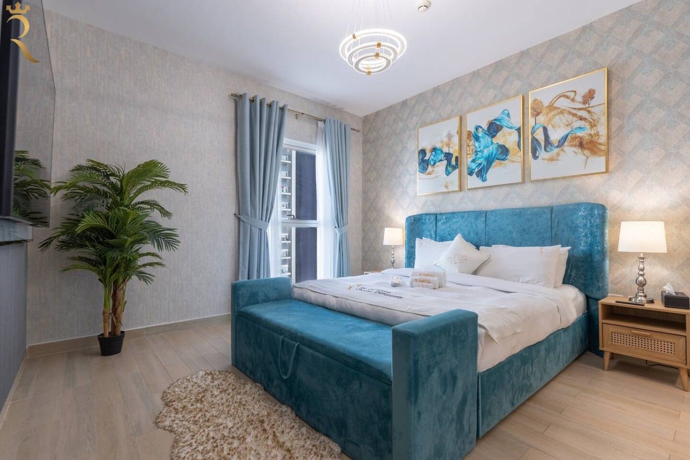 A bedroom with a bed, nightstands, a potted plant, and artwork on the wall.