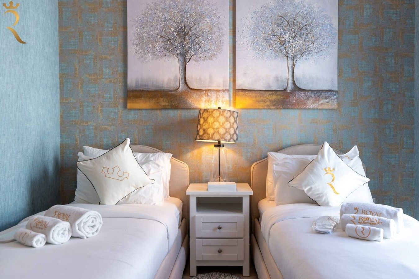 Habitación de hotel con dos camas, una mesita de noche, una lámpara y una obra de arte en la pared.