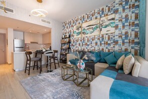 Una sala moderna con un sofá seccional, una mesa de centro y un comedor con taburetes de bar.